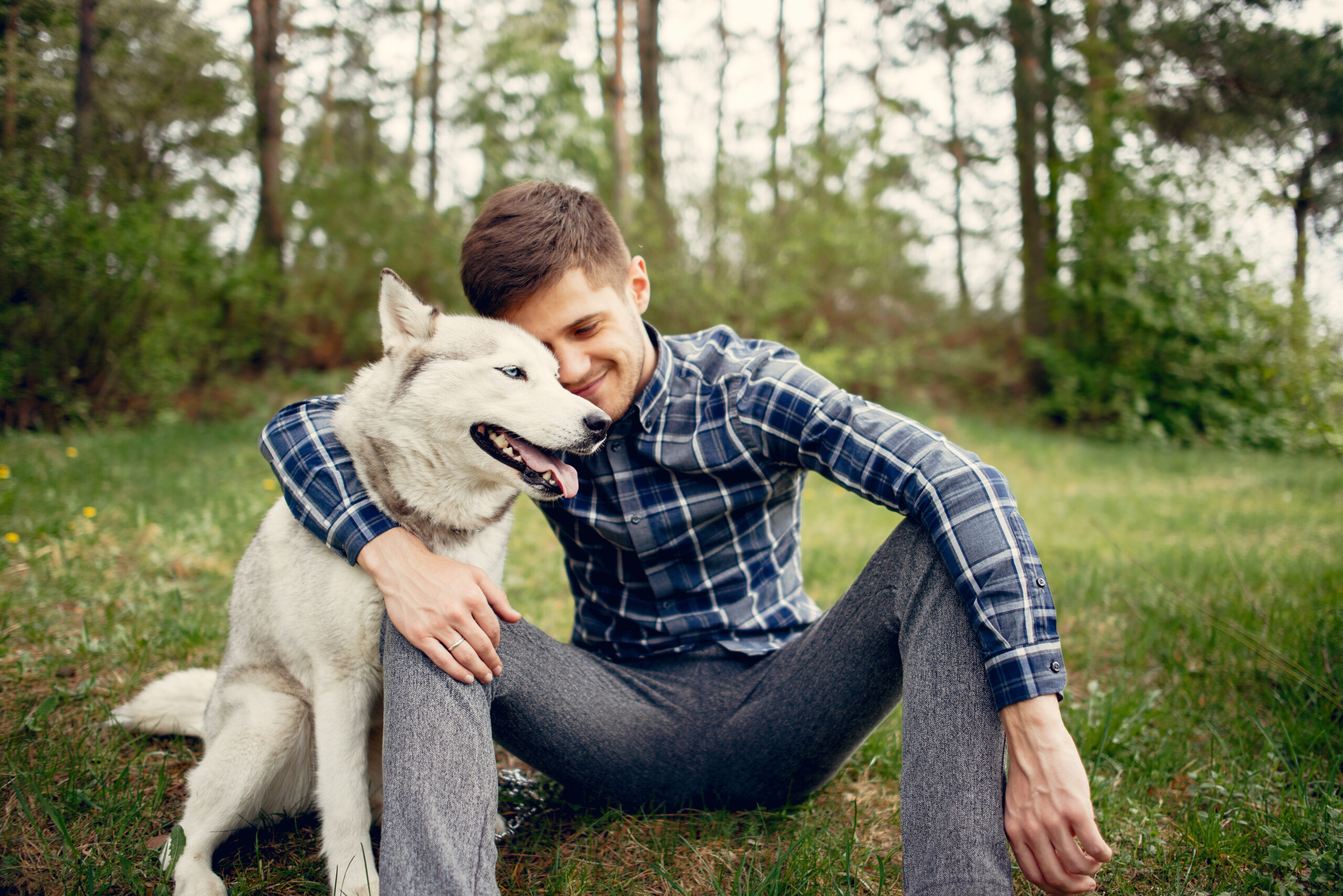 A person sitting in a park with their dog, sharing a close bond.