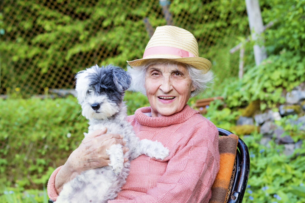 Elderly woman holding her dog, showing the emotional connection and benefits of pet therapy for elderly patients in hospice care.