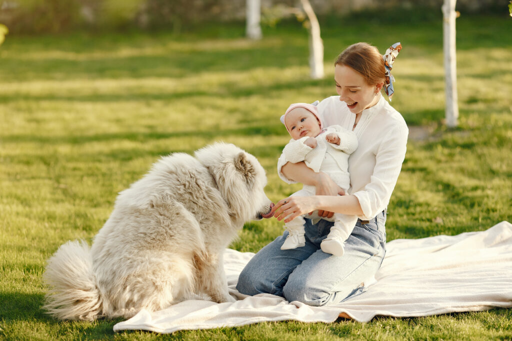 New mother with baby and therapy dog in the garden, providing emotional support for postpartum psychosis treatment and well-being.