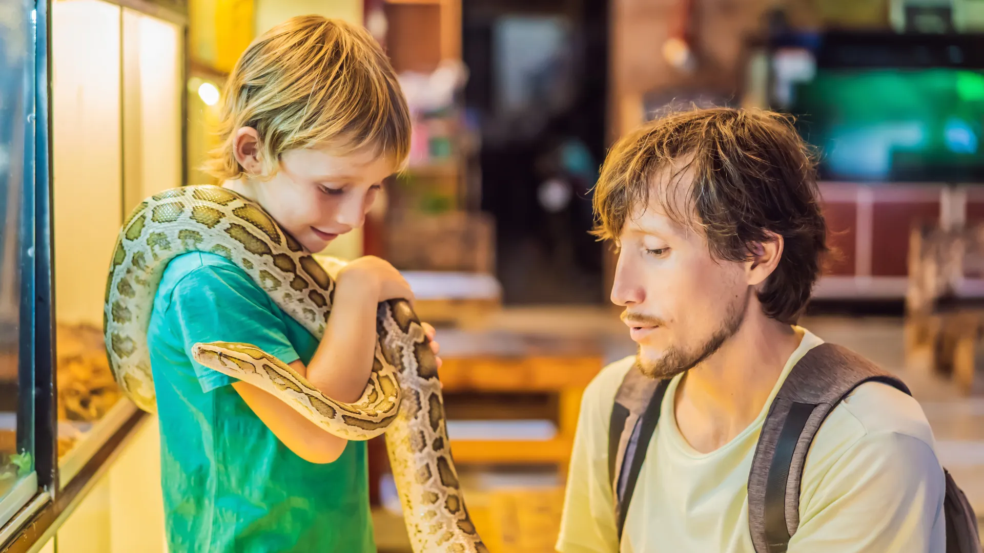 Best snakes to have as pets being handled by a child and an adult in a reptile store.